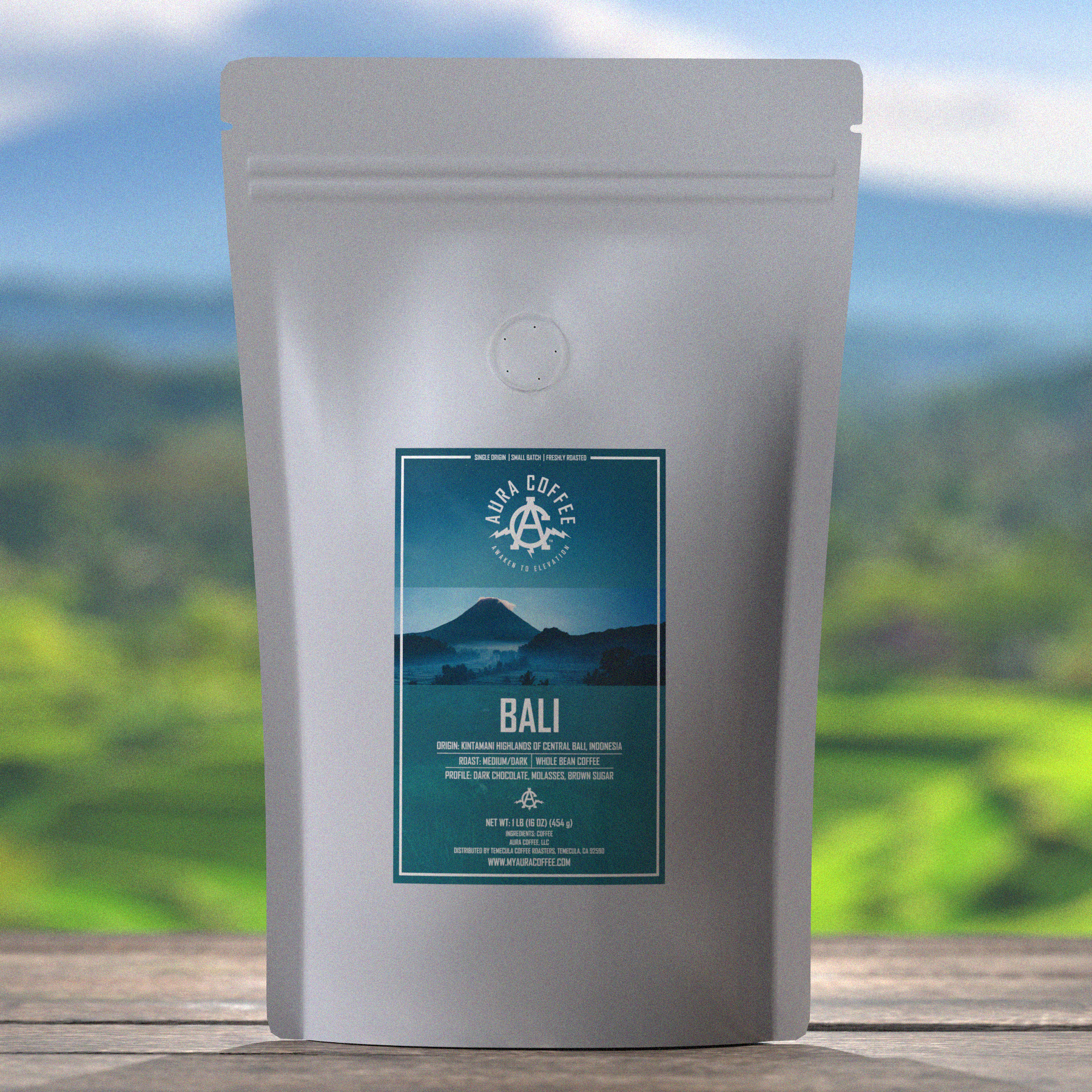 Aura Bali Single Origin Coffee Pouch sitting on wooden table with green fields and mountains in the background