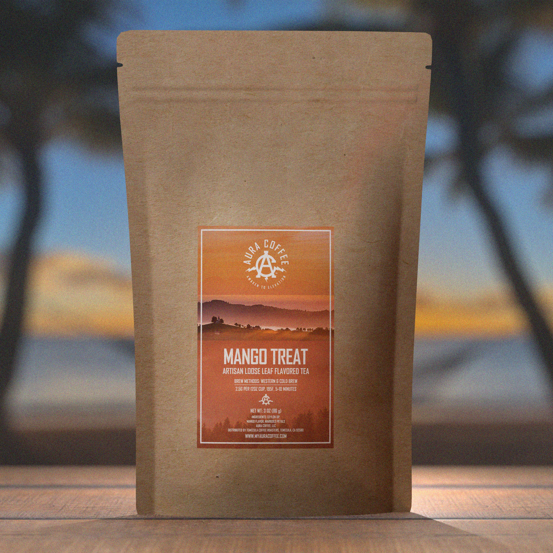 Pouch of Aura Coffee Mango Treat Tea Blend on a dock with palm trees and a beach in the background